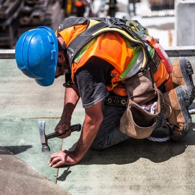 man wearing blue hard hat using hammer 544966